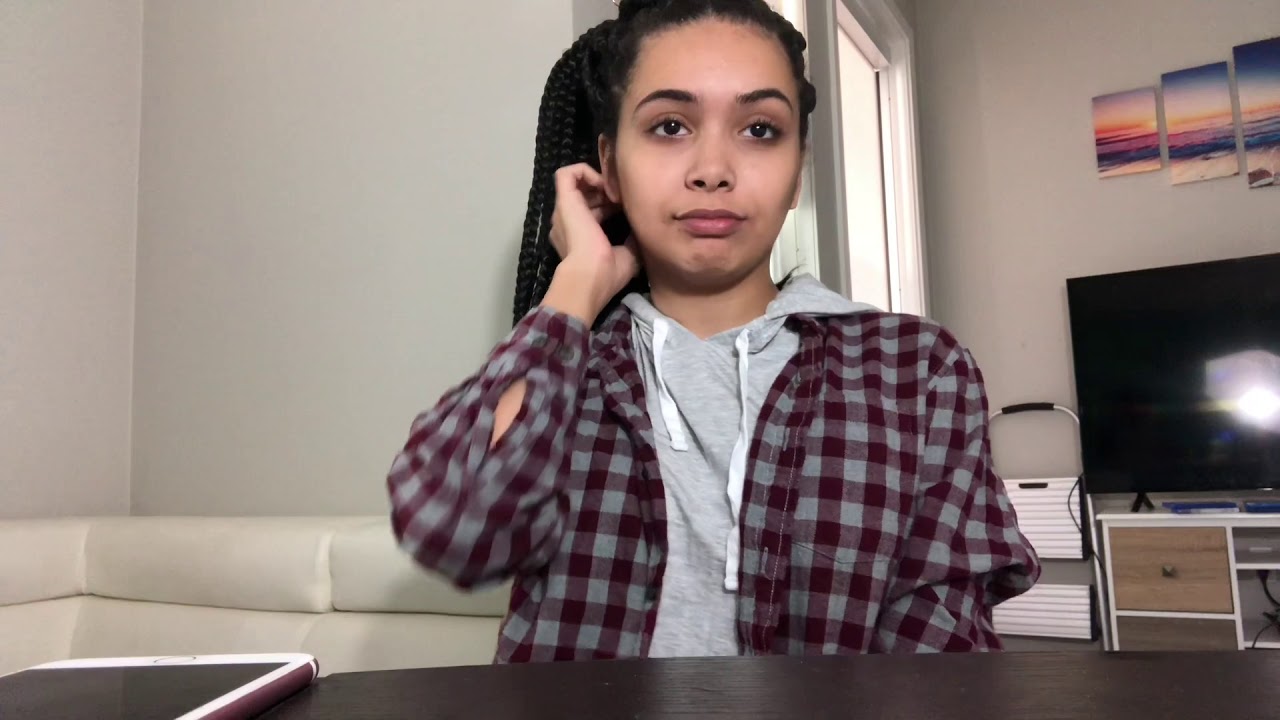 Una imagen de su propio vídeo, en un entorno cotidiano, con camisa de cuadros y trenzas.